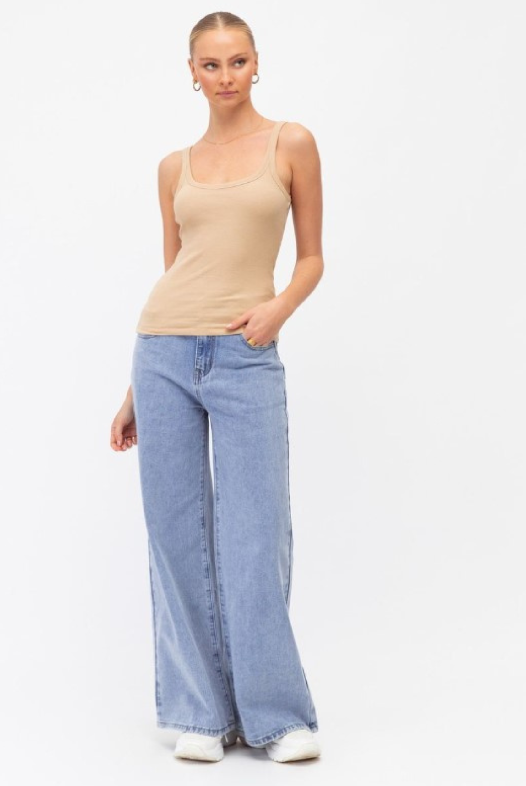 Model wearing a neutral tank with lightwash denim jeans