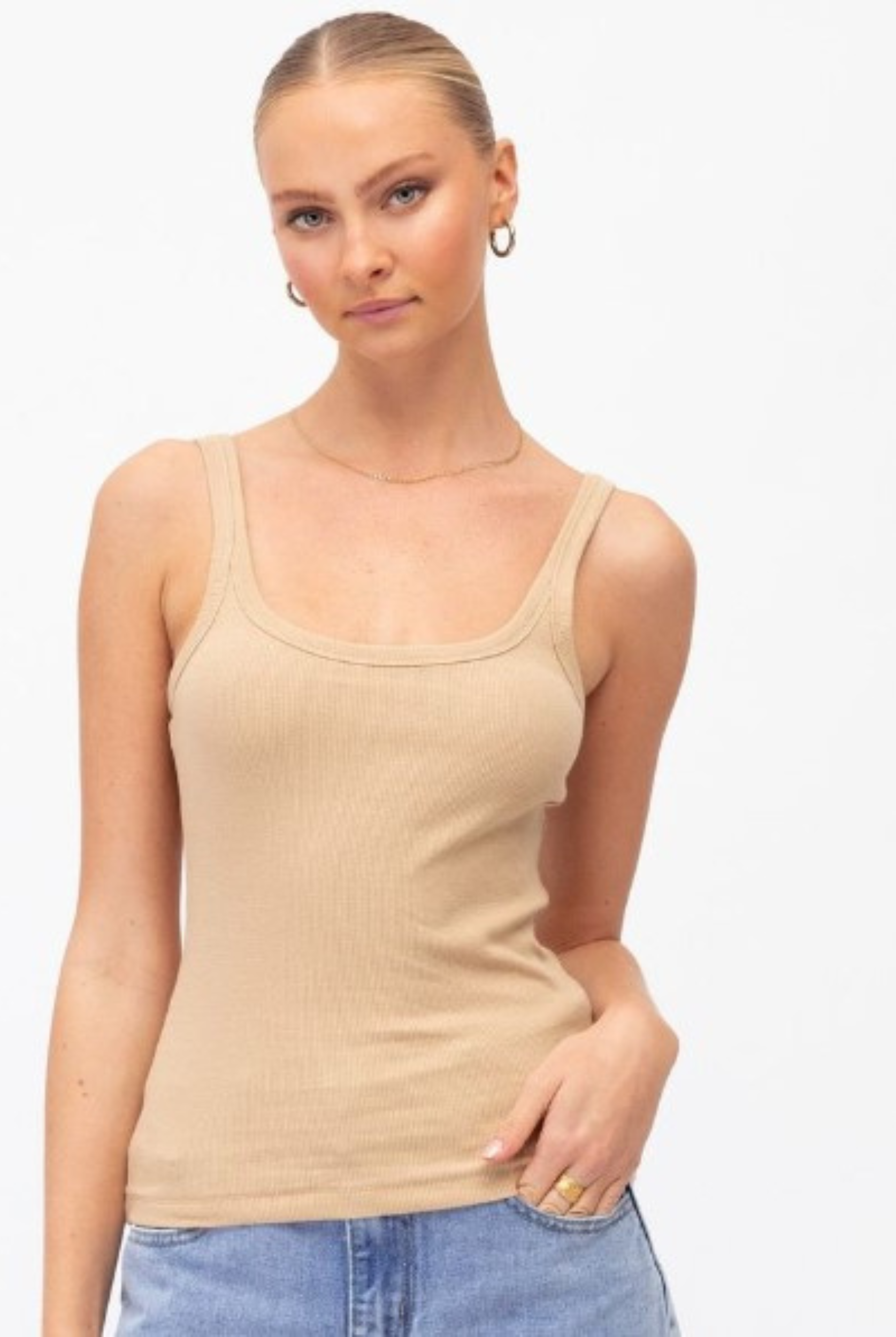 Model wearing a neutral tank with lightwash denim jeans