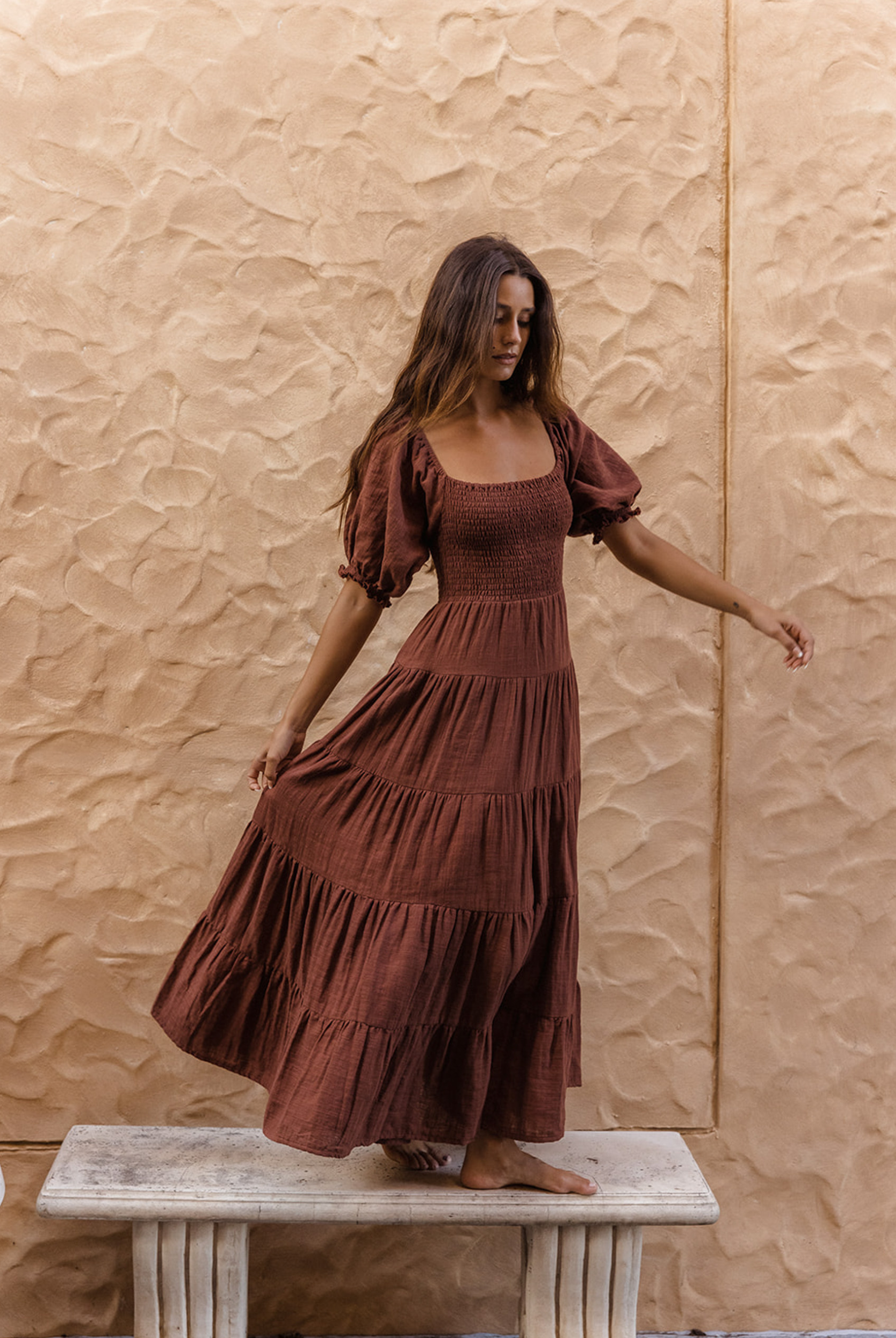 Model wearing chocolate brown tiered dress with short puffy sleeves