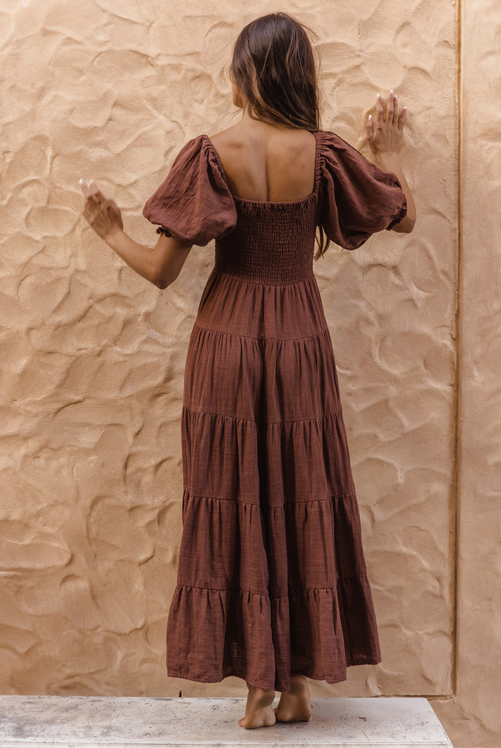 Model wearing chocolate brown tiered dress with short puffy sleeves