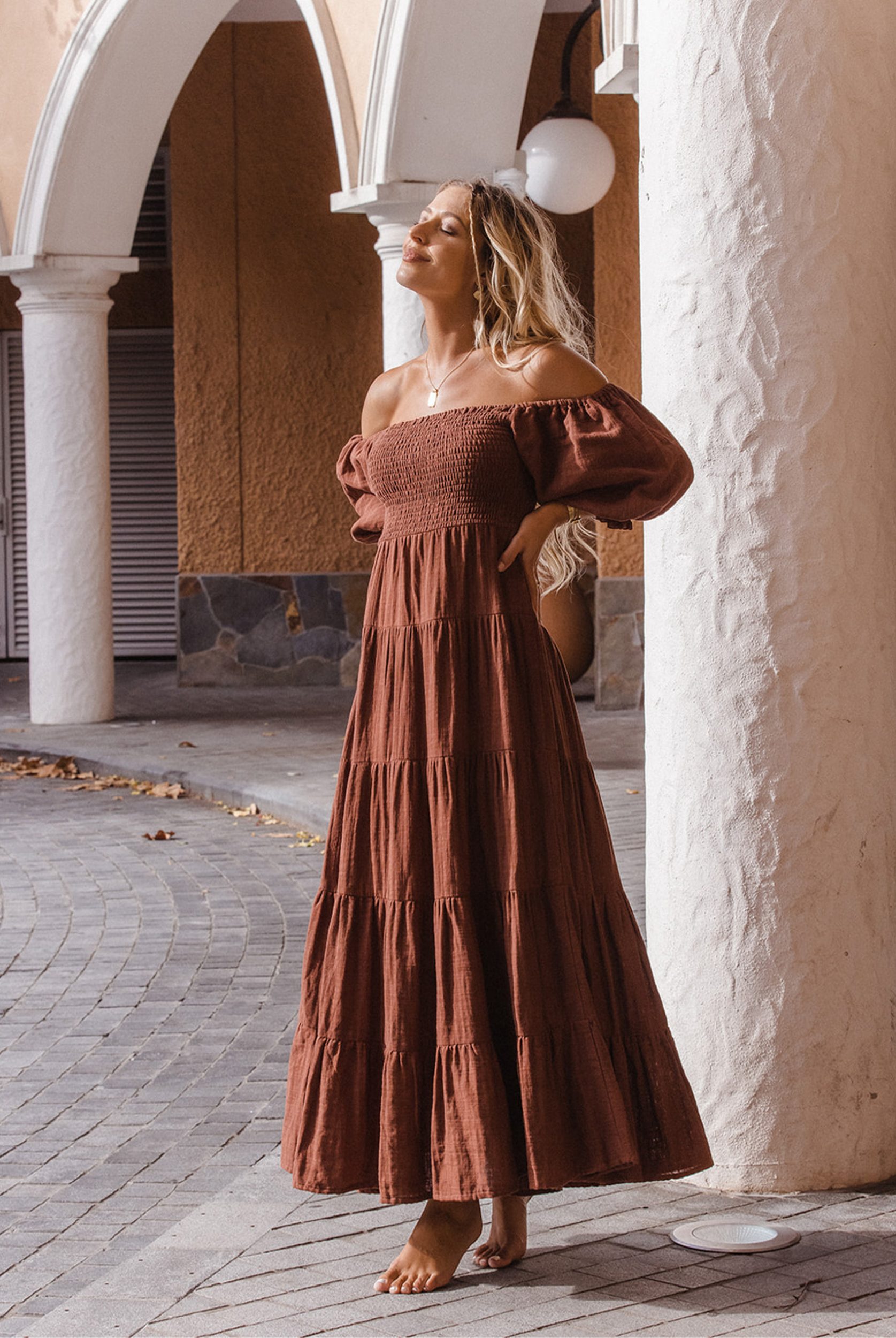 Model wearing chocolate brown tiered dress with short puffy sleeves