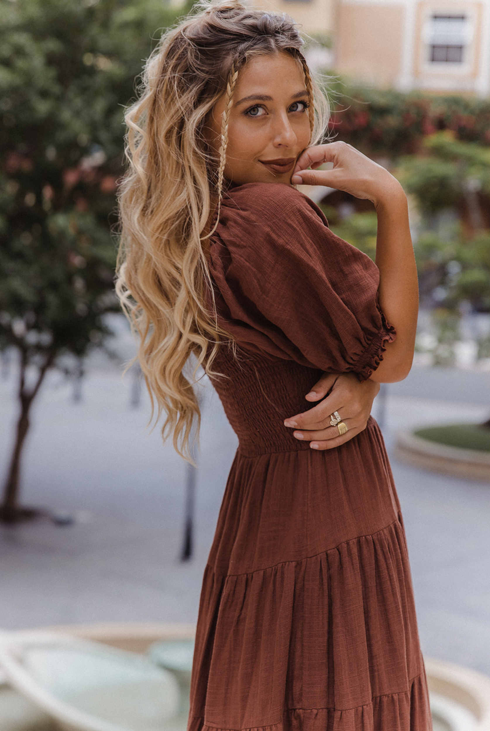 Model wearing chocolate brown tiered dress with short puffy sleeves