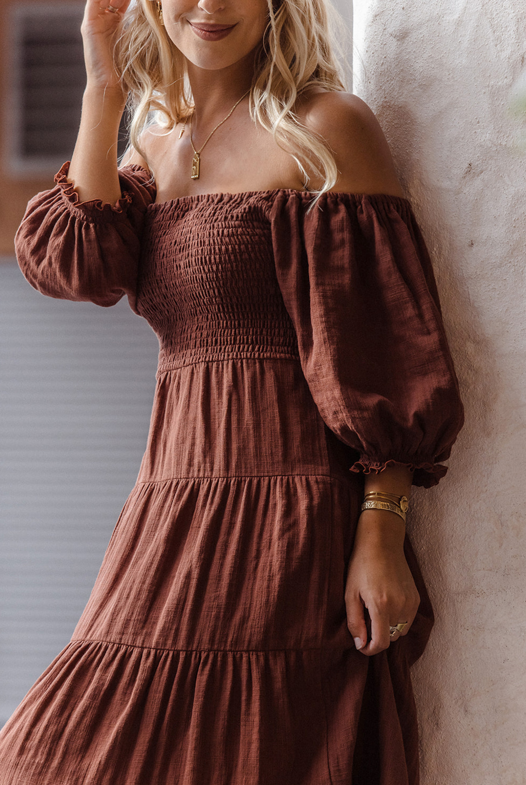 Model wearing chocolate brown tiered dress with short puffy sleeves