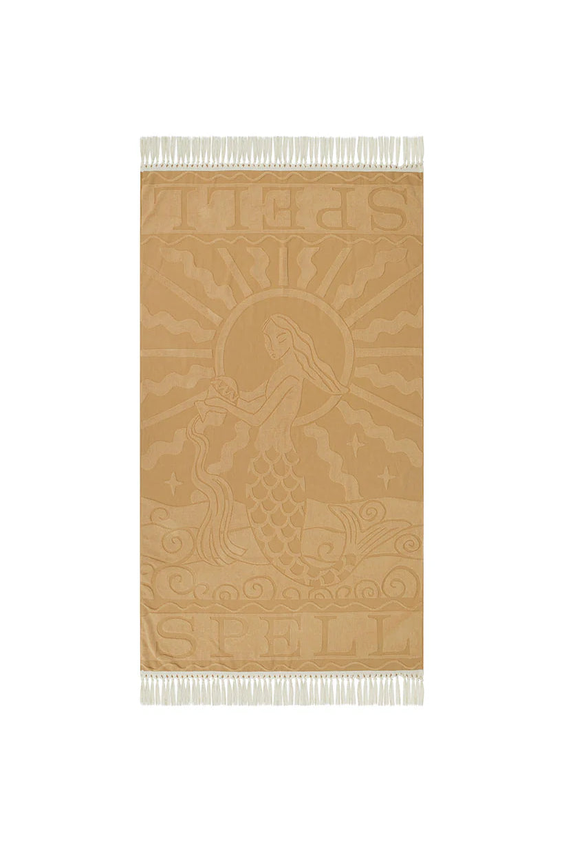 Beige towel with mermaid design and Spell branding on a white background