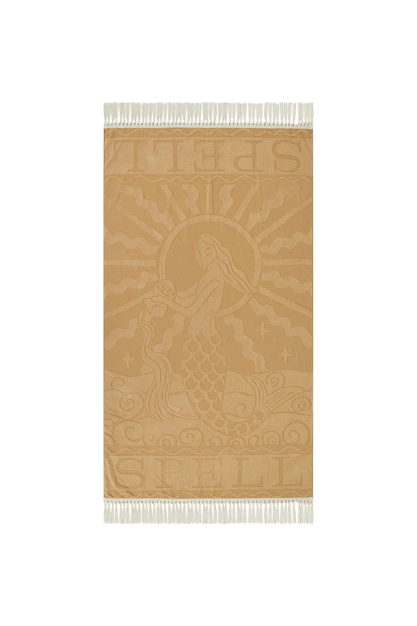 Beige towel with mermaid design and Spell branding on a white background