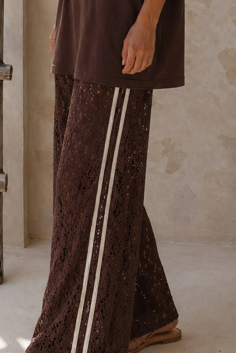 Brown lace pants with white stripes worn by a person against a neutral background
