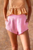 Person wearing a peach top and pink shorts against a beige background