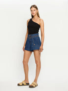Woman wearing a black top and blue denim shorts on a white background