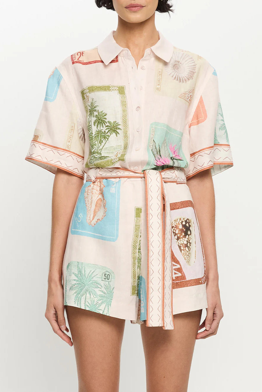 Woman wearing a patterned shirt with tropical designs on a plain background