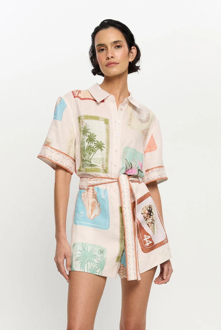 Woman wearing a patterned shirt and shorts with a white background