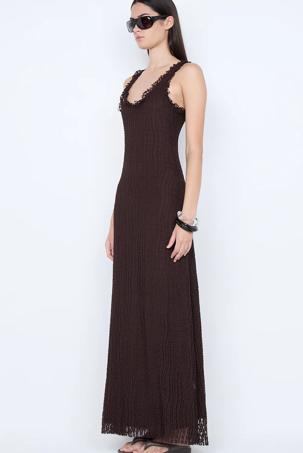 Woman wearing a brown sleeveless dress with lace details on a white background