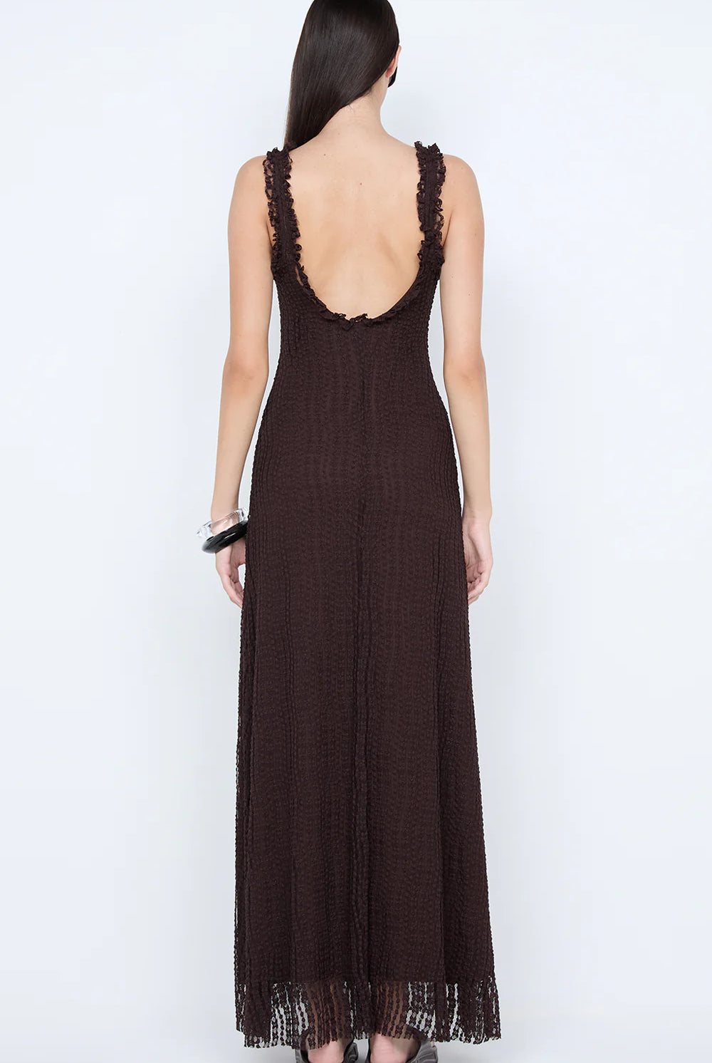 Woman wearing a brown lace-trimmed dress on a white background