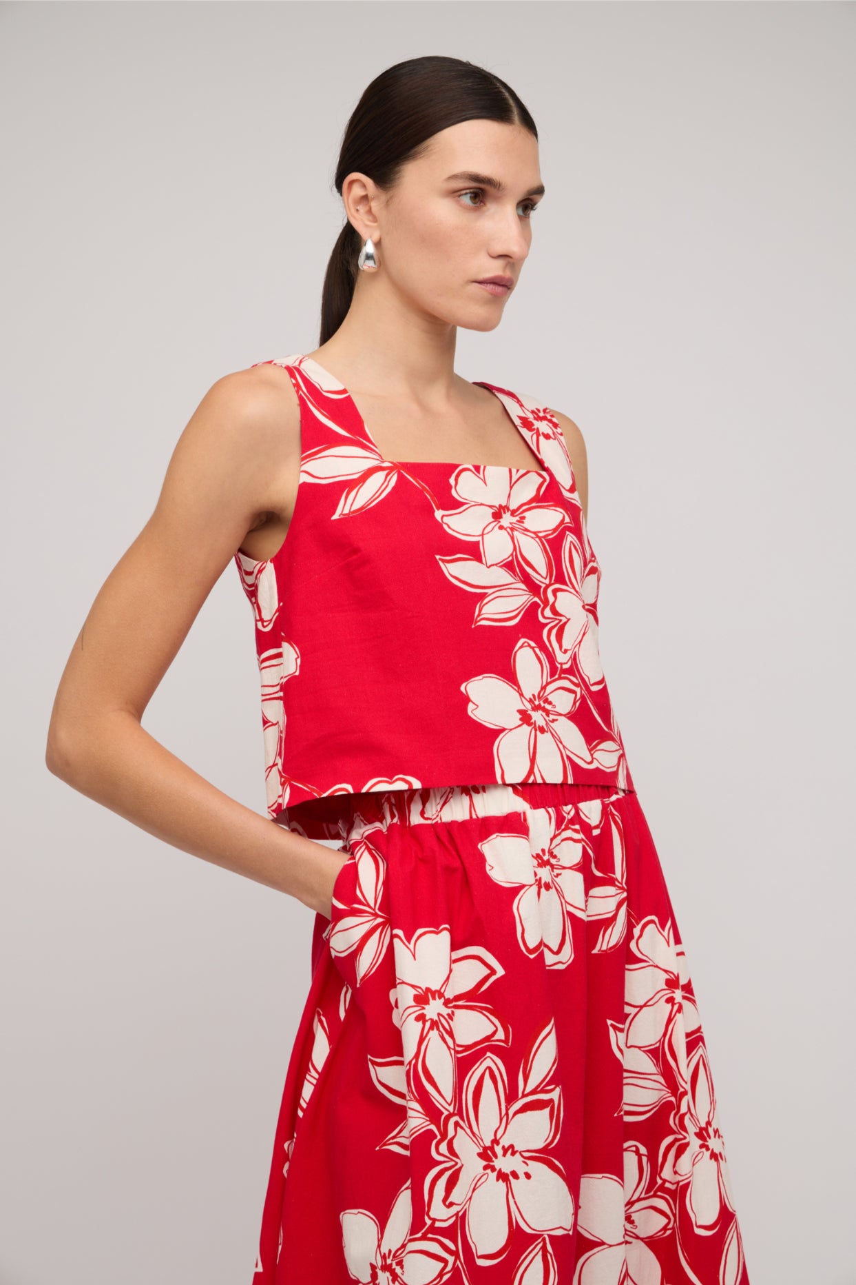 Woman wearing a red floral dress against a gray background
