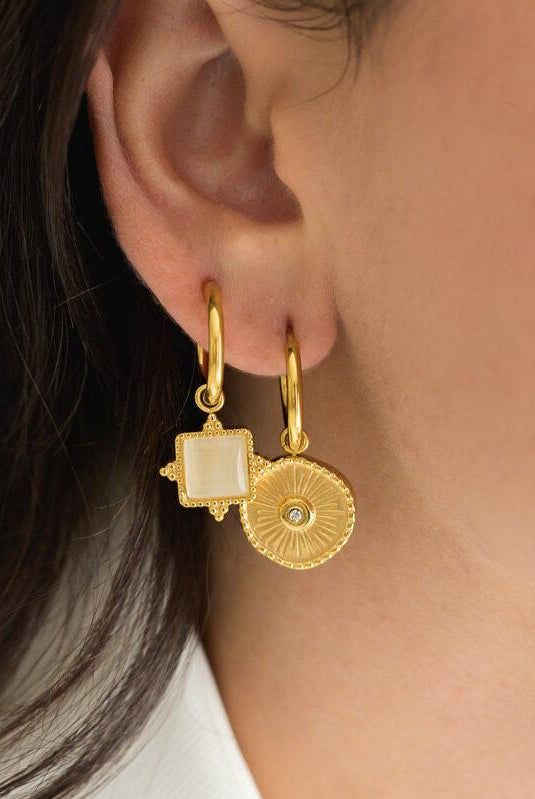 Gold earrings worn by a person with dark hair.