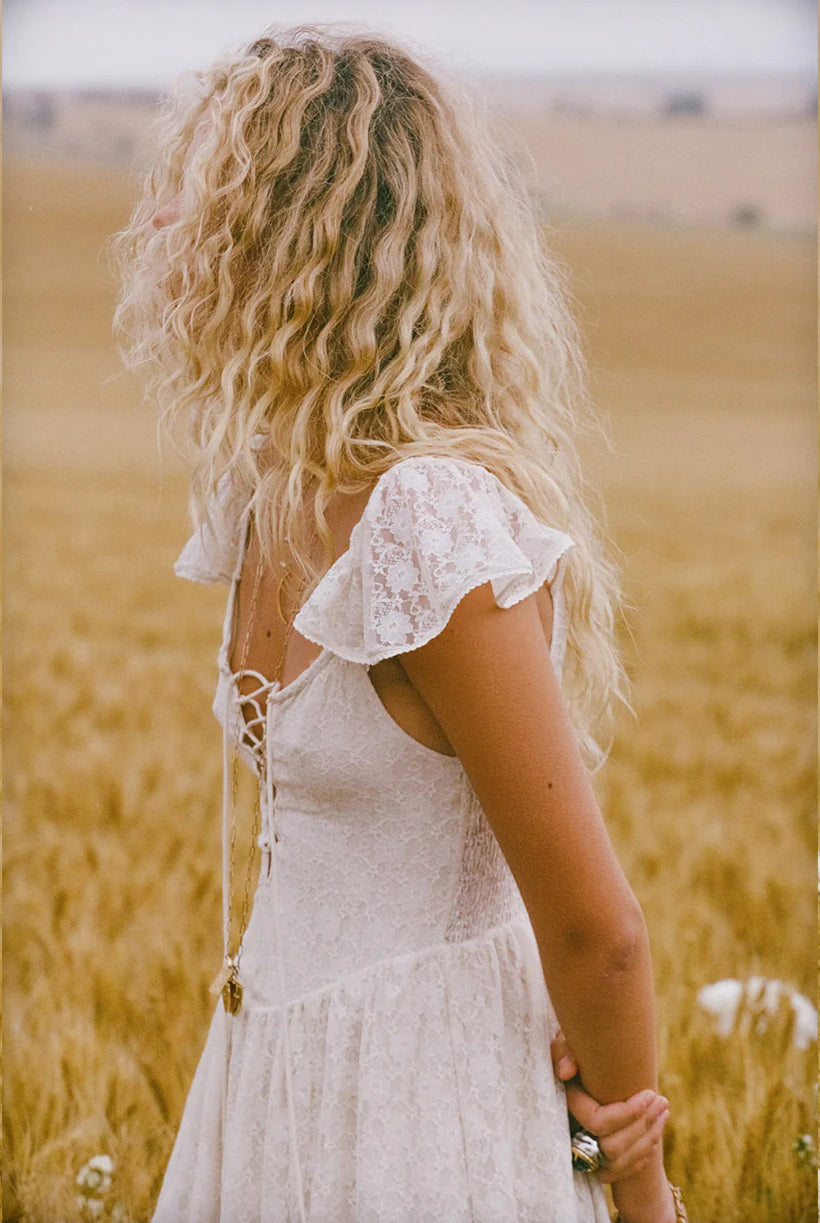 Woman in a white dress standing in a field of tall grass