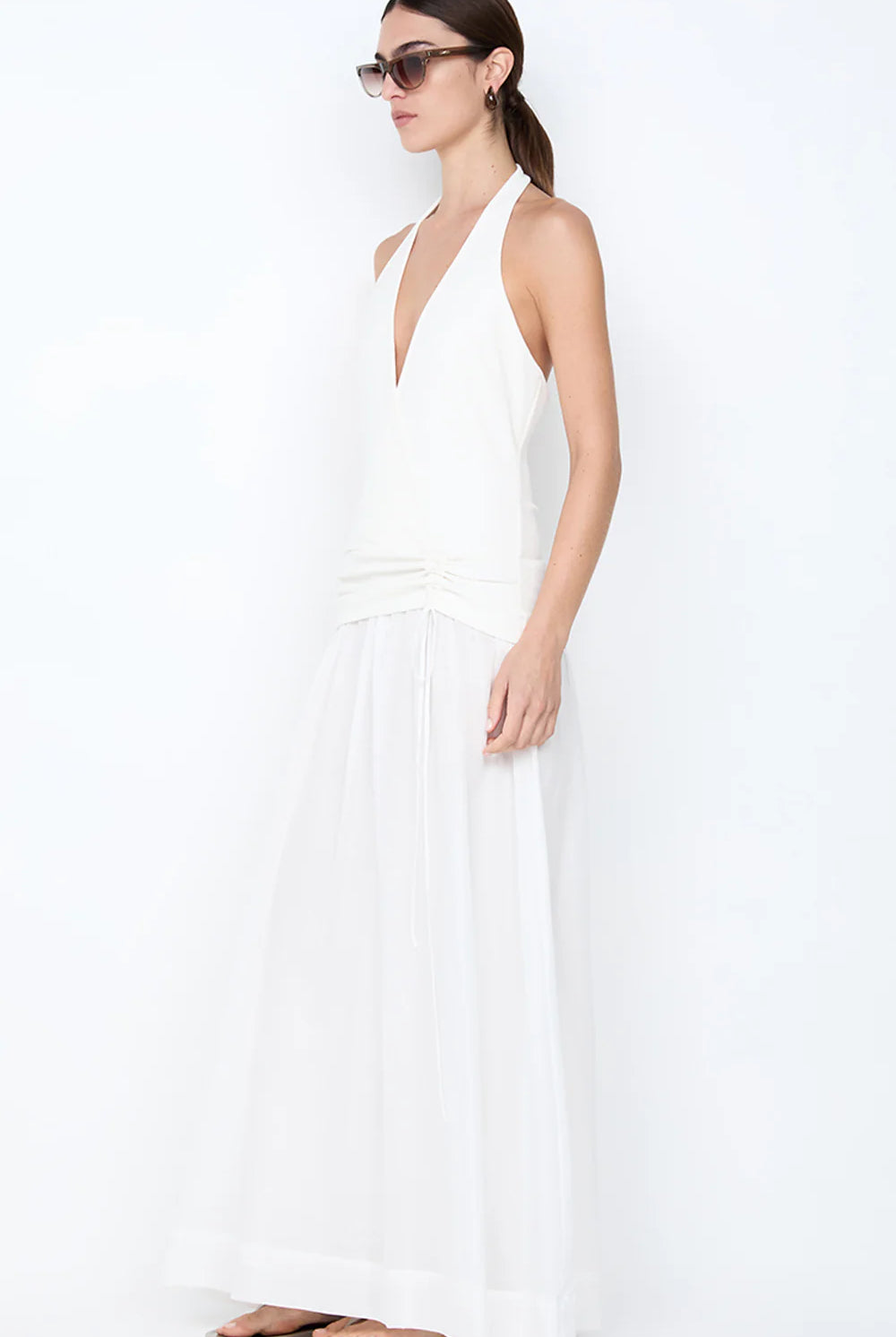 Woman wearing a white halter neck dress on a white background