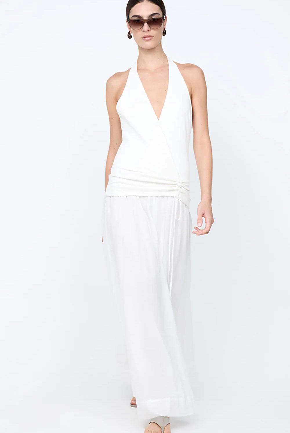 Woman wearing a white halter neck dress on a white background