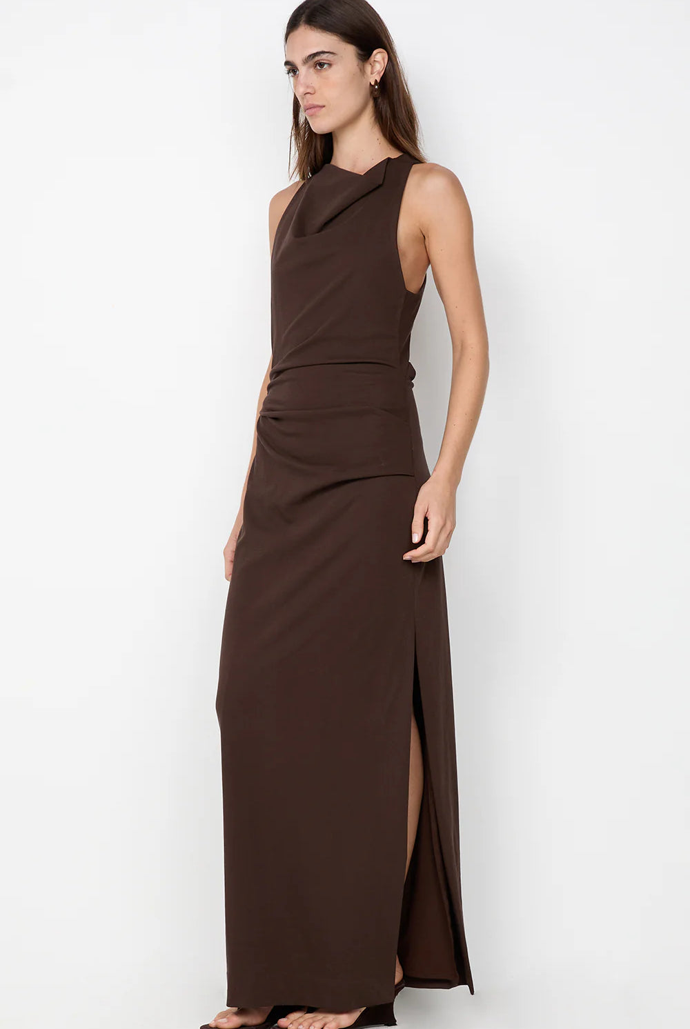 Woman wearing a brown dress with a slit on a white background
