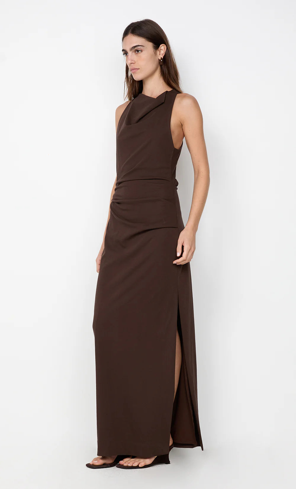 Woman wearing a brown dress with a slit on a white background