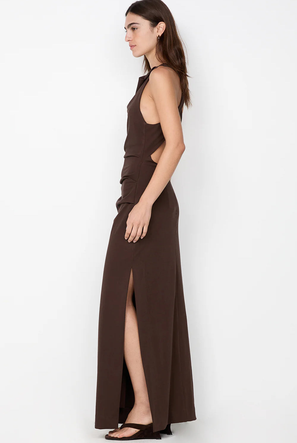 Woman wearing a brown halter neck dress with a slit on a white background