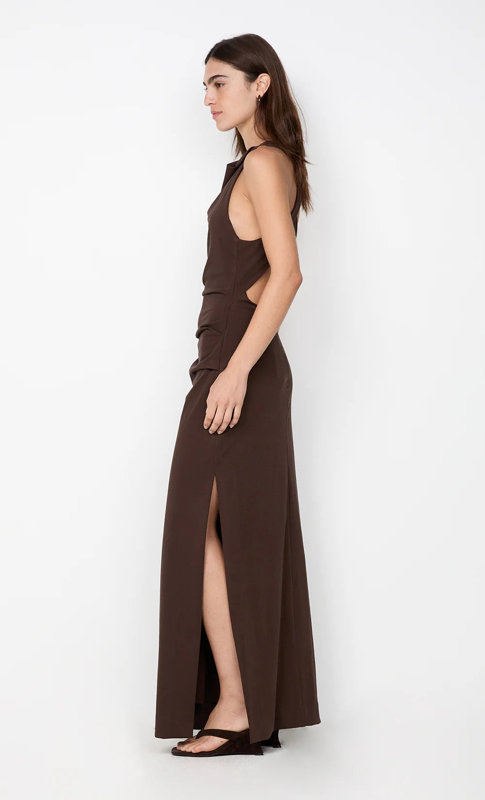 Woman wearing a brown halter neck dress with a slit on a white background