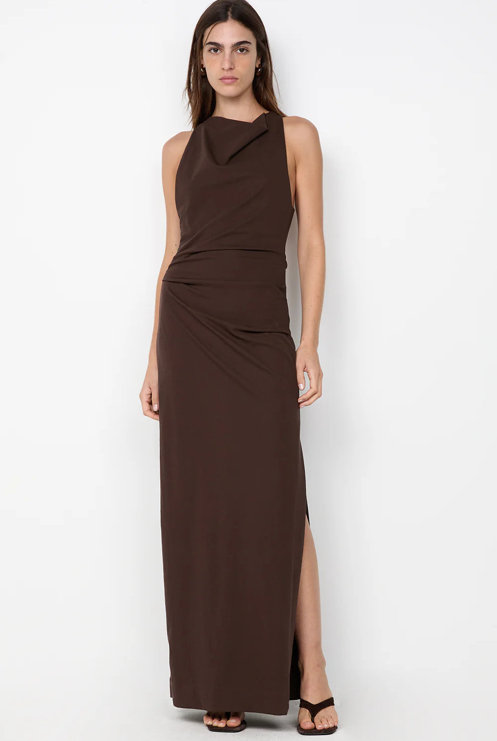 Woman wearing a brown sleeveless dress with a slit on a white background