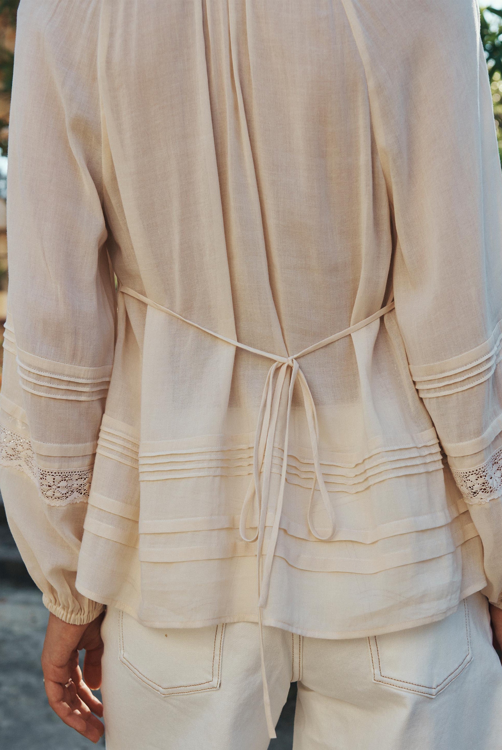 Beige outfit with lace details on a blurred natural background
