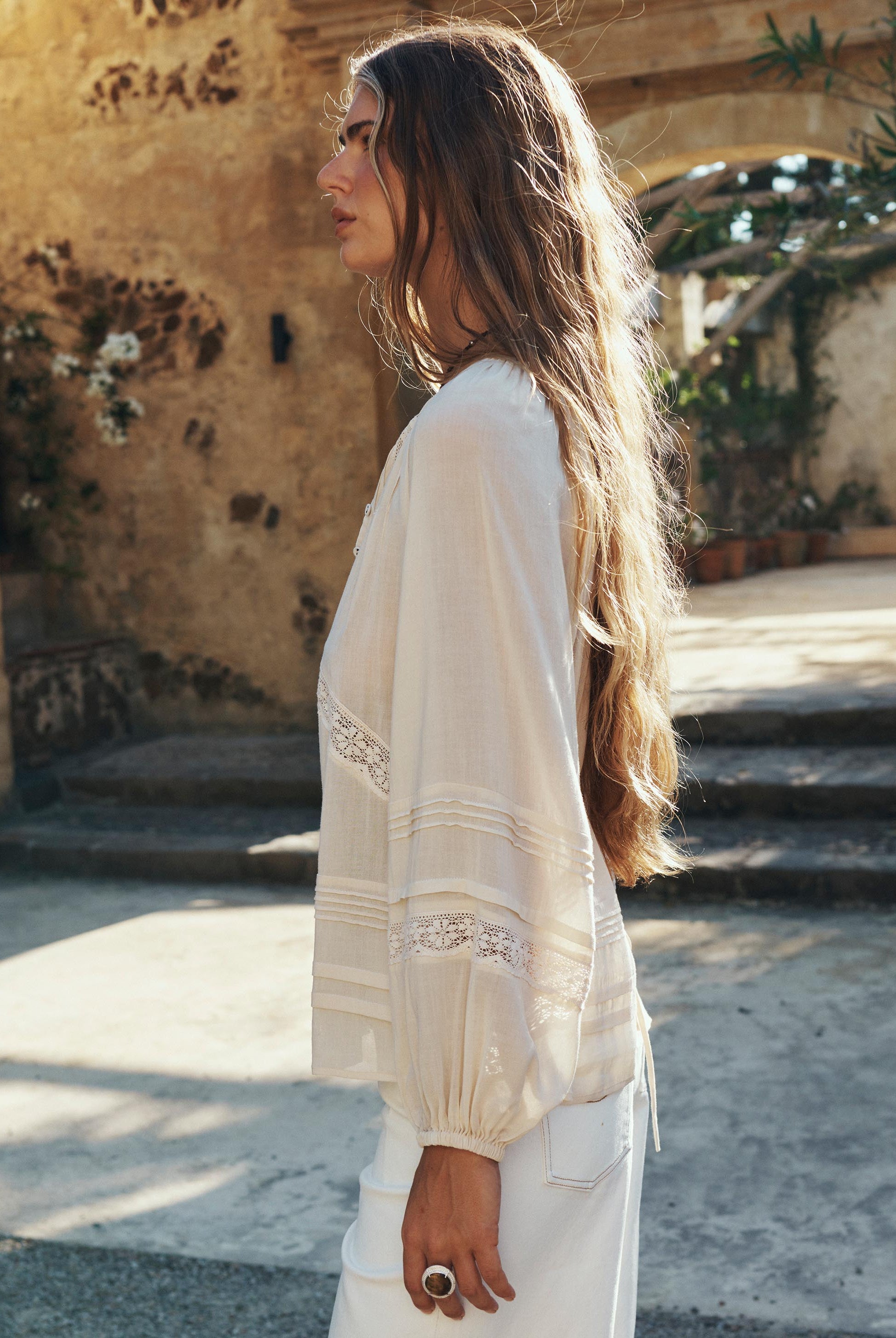 Woman wearing a white blouse with embellishments in an outdoor setting