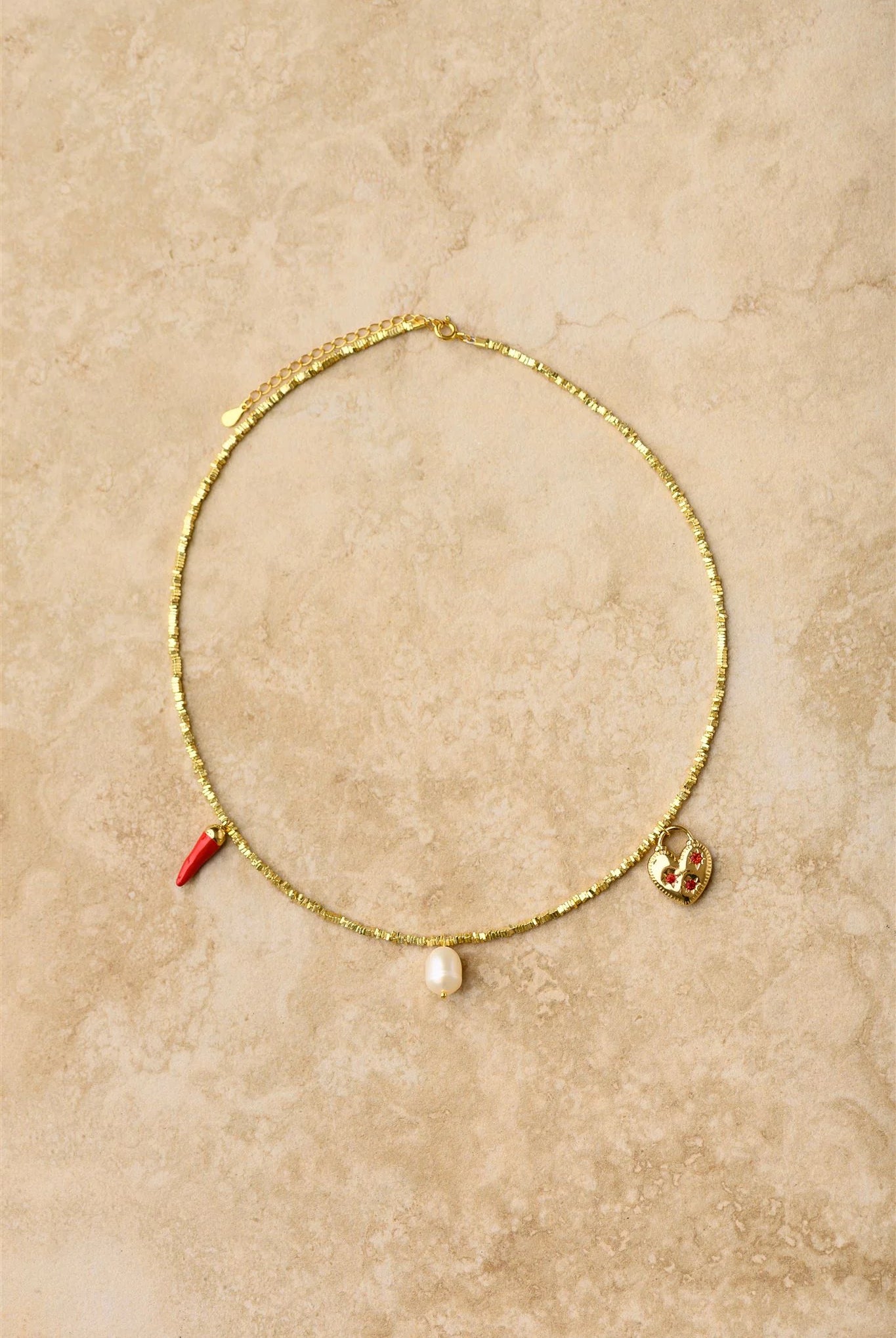 Gold necklace with charms on a beige textured background