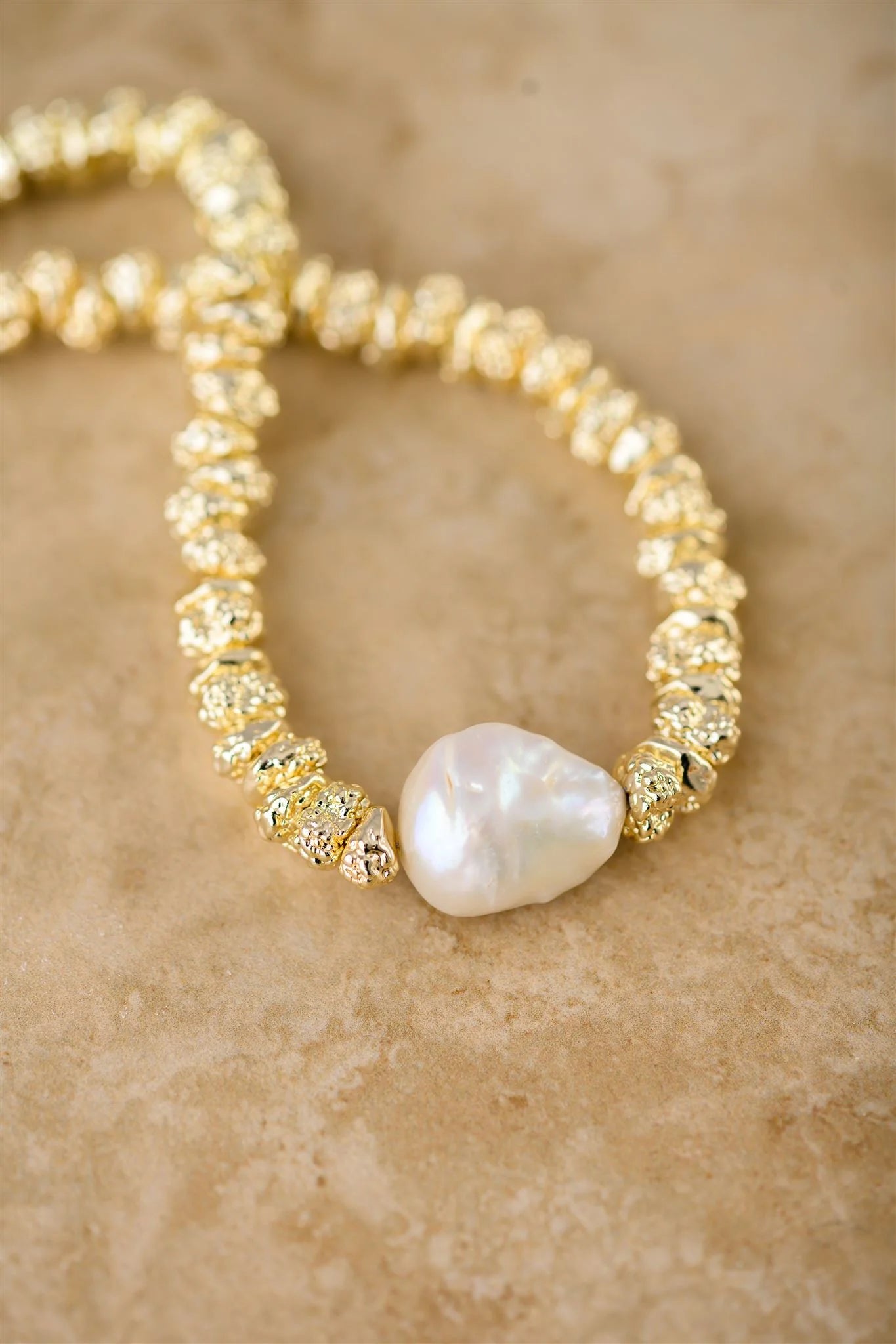 Pearl necklace with gold accents on a beige surface