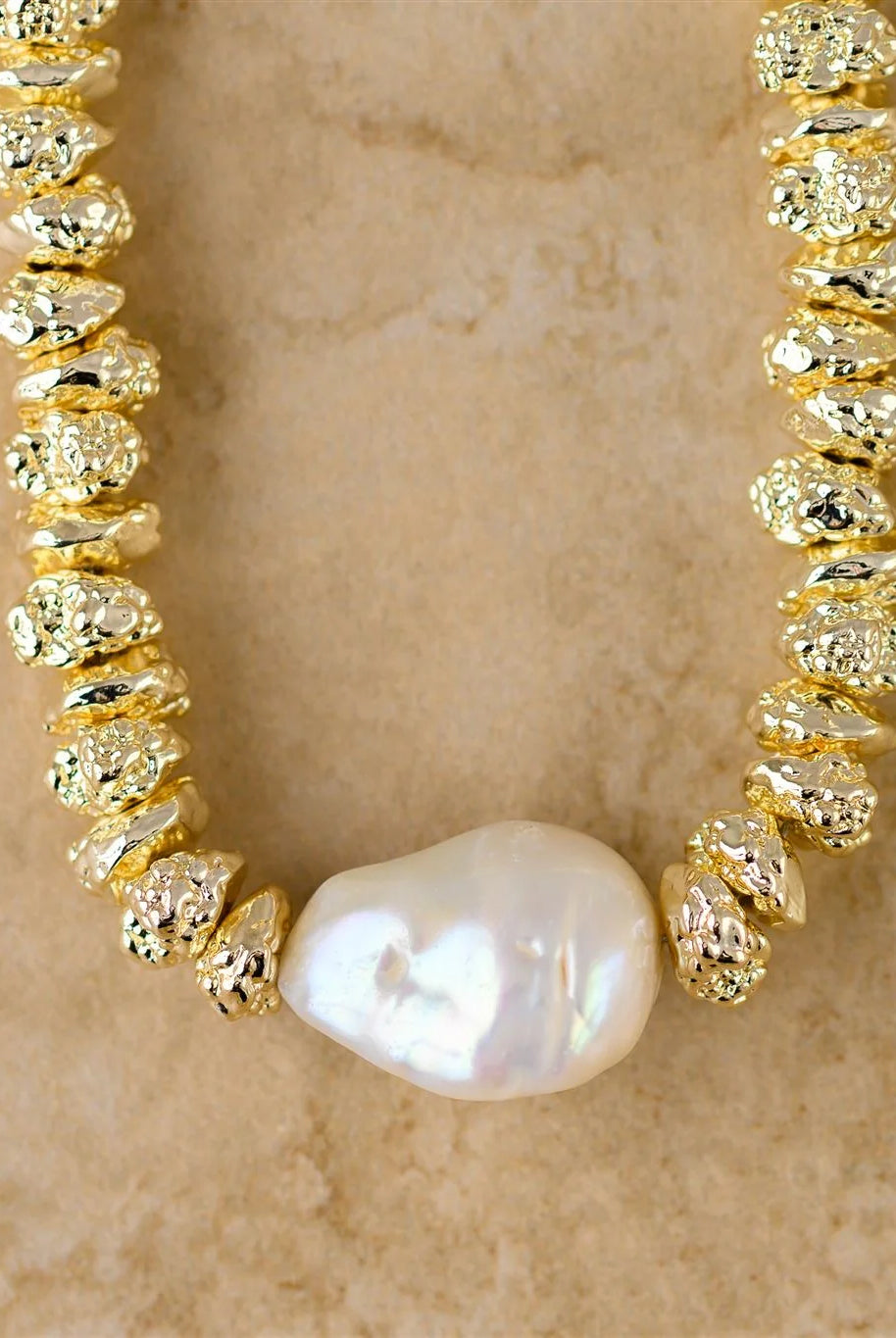 Gold necklace with a pearl on a beige background