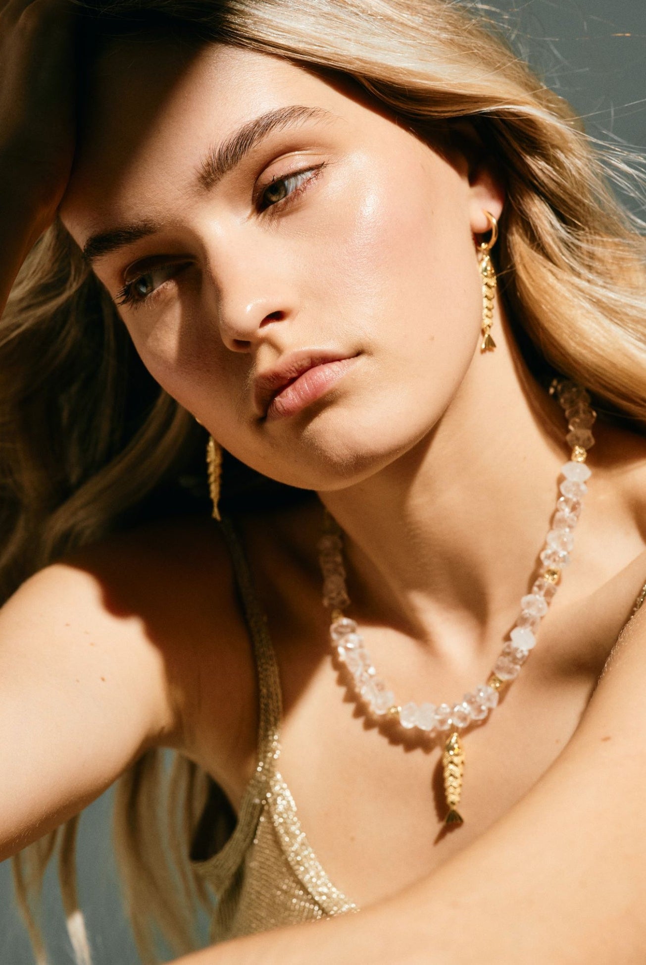 Woman wearing gold jewelry including earrings and a necklace.