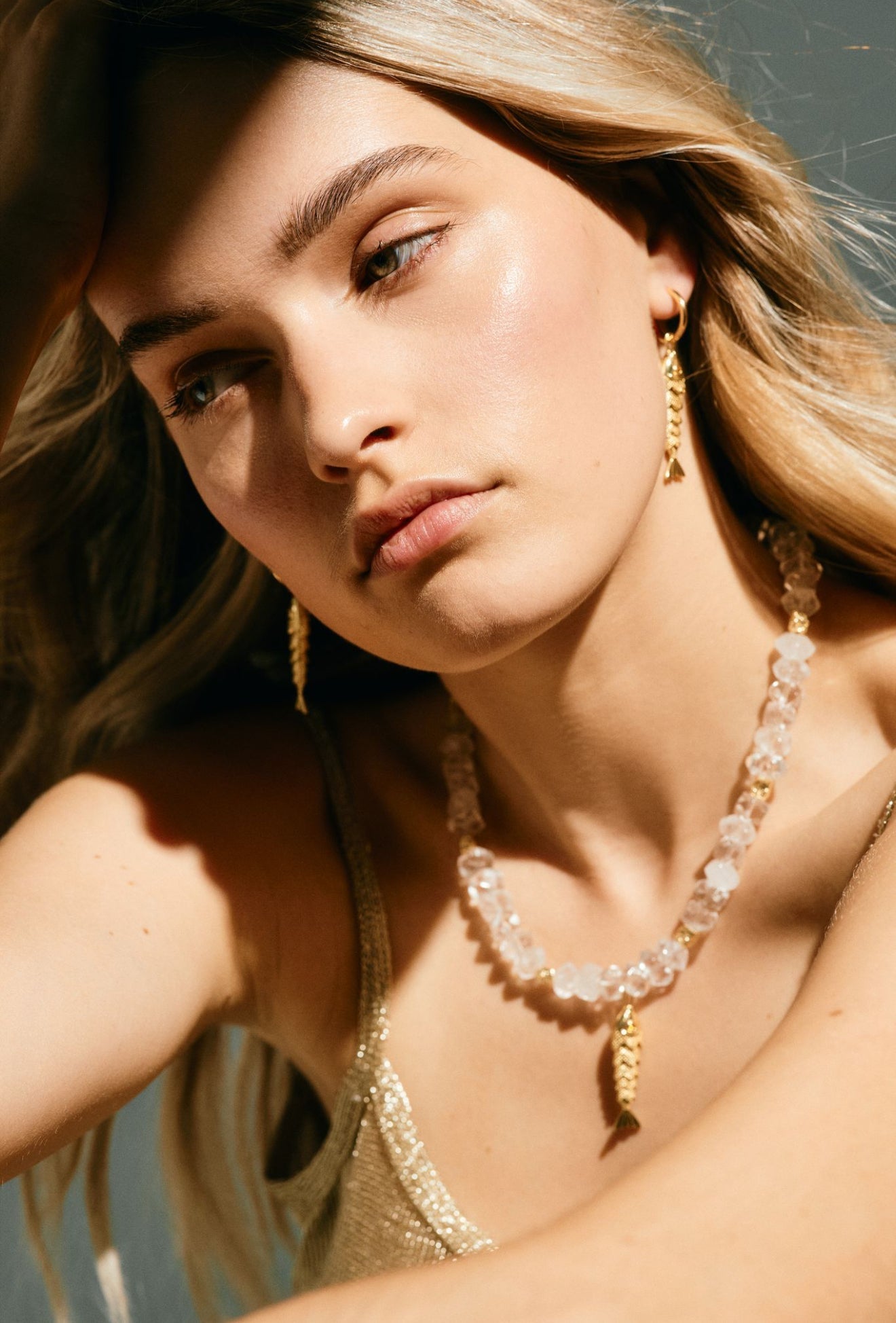 Woman wearing gold jewelry including earrings and a necklace.
