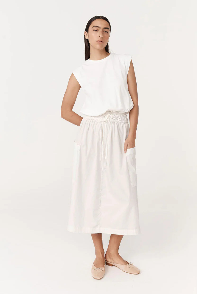 Woman wearing a white sleeveless top and white pants on a white background