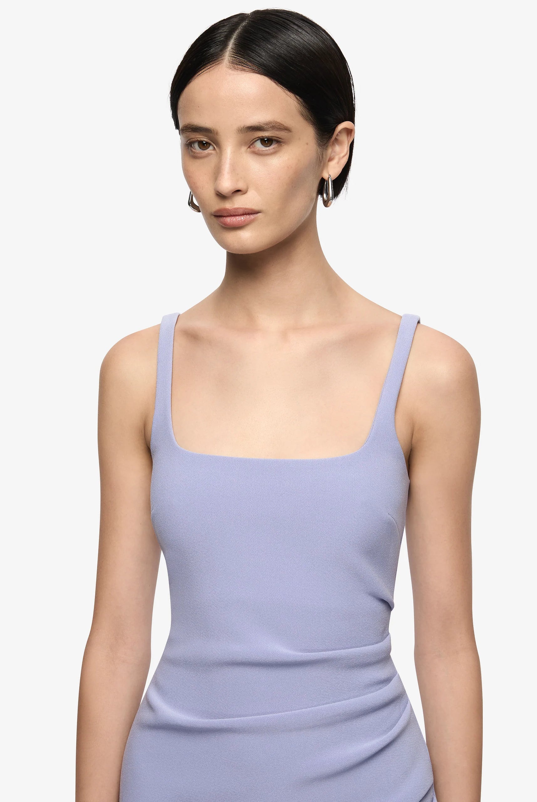 Woman wearing a light purple sleeveless dress against a plain background