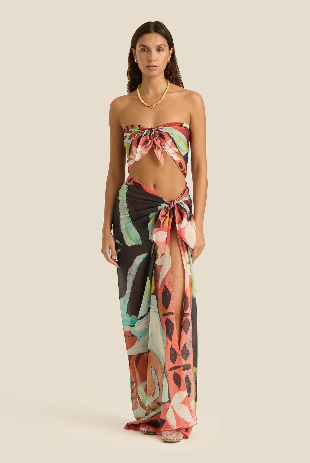 Woman wearing a colorful strapless dress with a pattern on a beige background