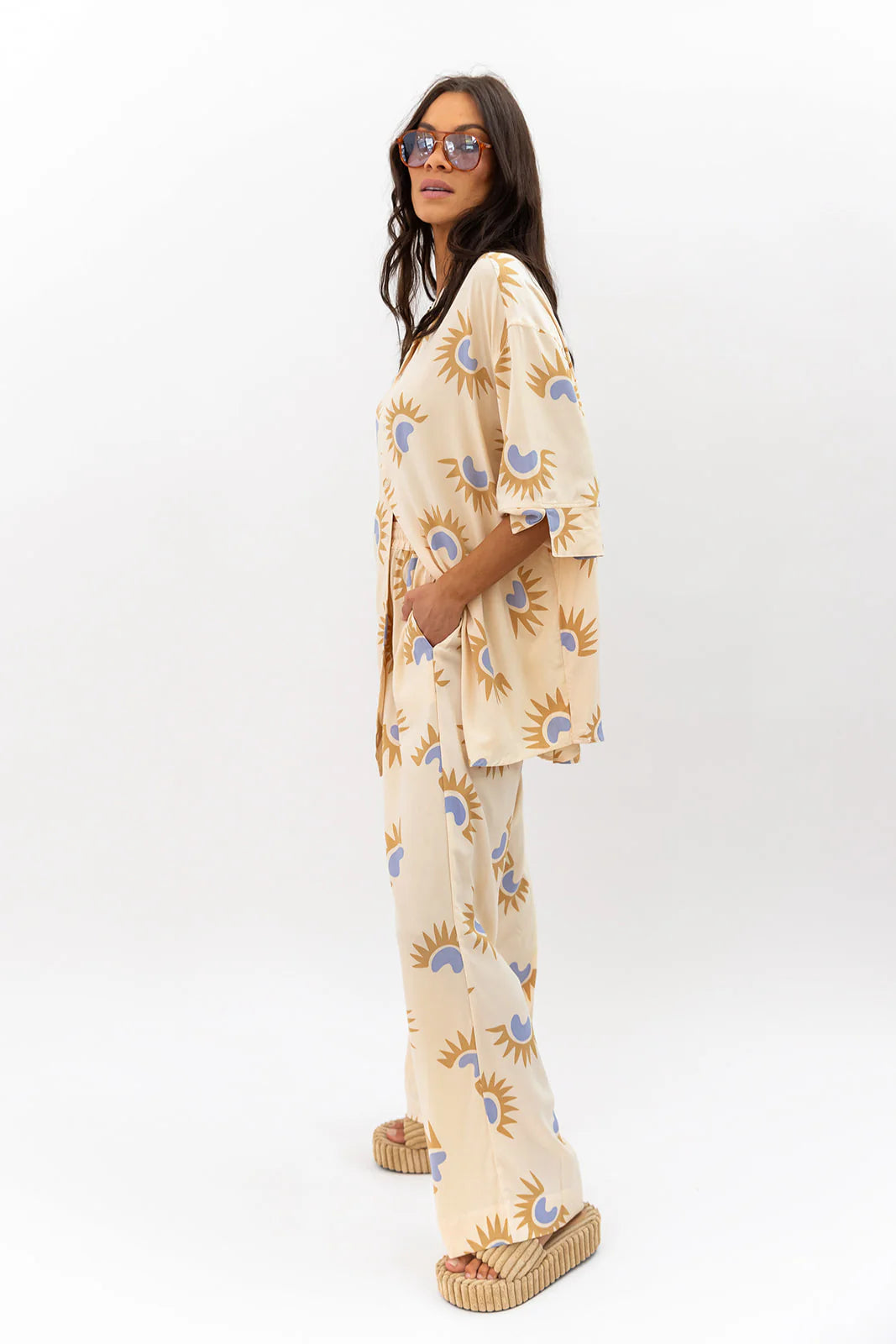 Woman wearing a neutral patterned outfit on a white background