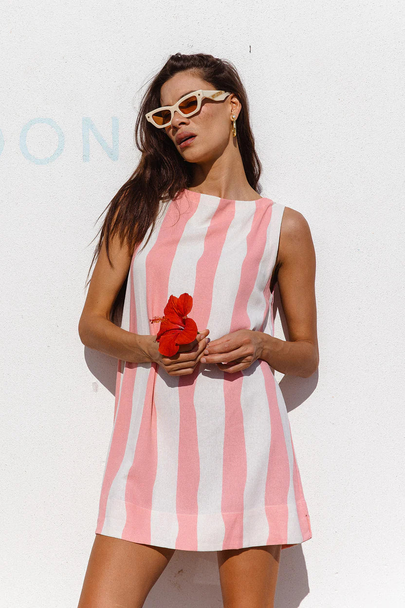 Woman wearing a pink and white striped dress holding a red flower against a white background