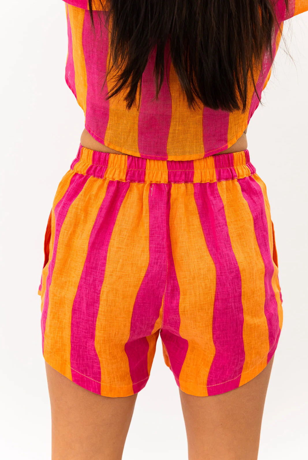 Person wearing a colorful striped outfit with pink and orange vertical stripes on a white background