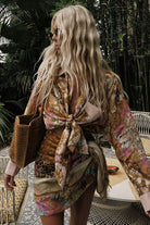 Woman in a patterned dress standing outdoors with plants in the background
