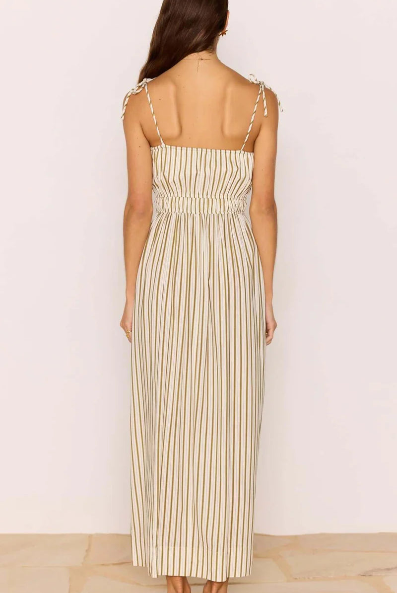 Woman wearing a striped dress with thin straps on a plain background