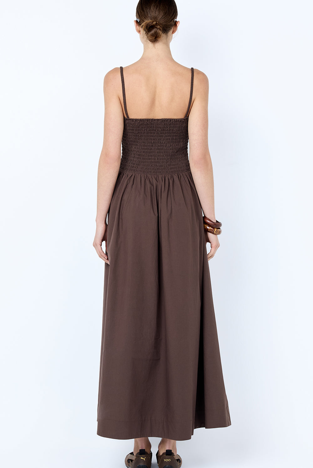 Woman wearing a brown dress with thin straps on a white background