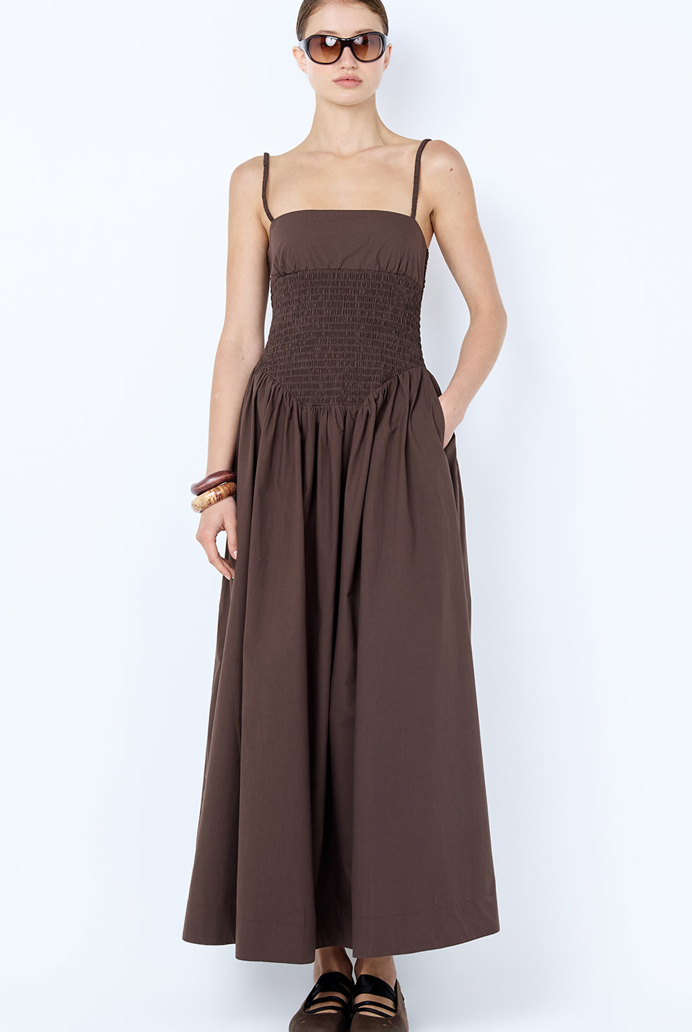 Woman wearing a brown dress with sunglasses on a white background