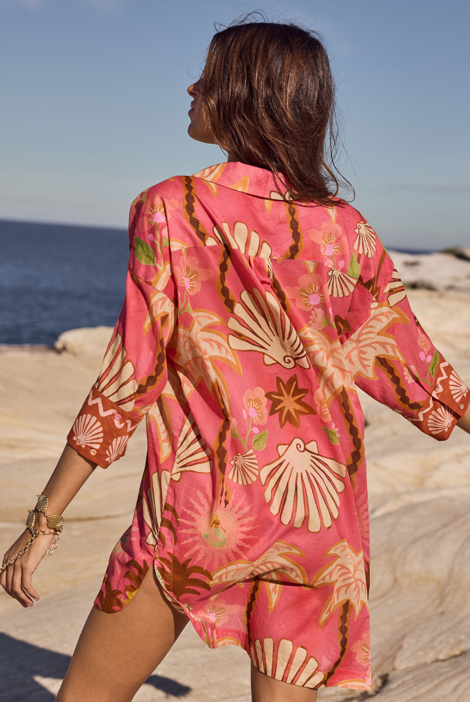 Woman wearing a pink floral kimono on a beach