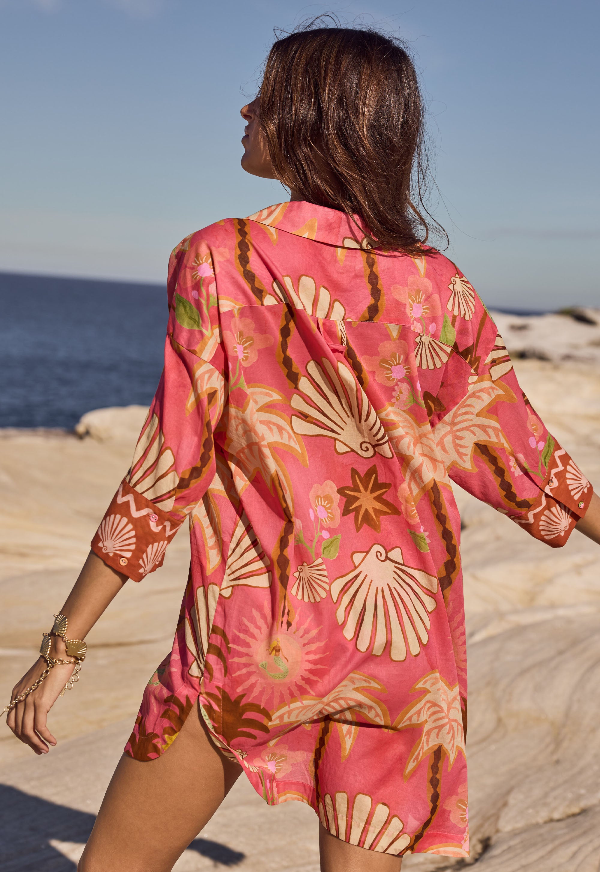 Woman wearing a pink floral kimono on a beach
