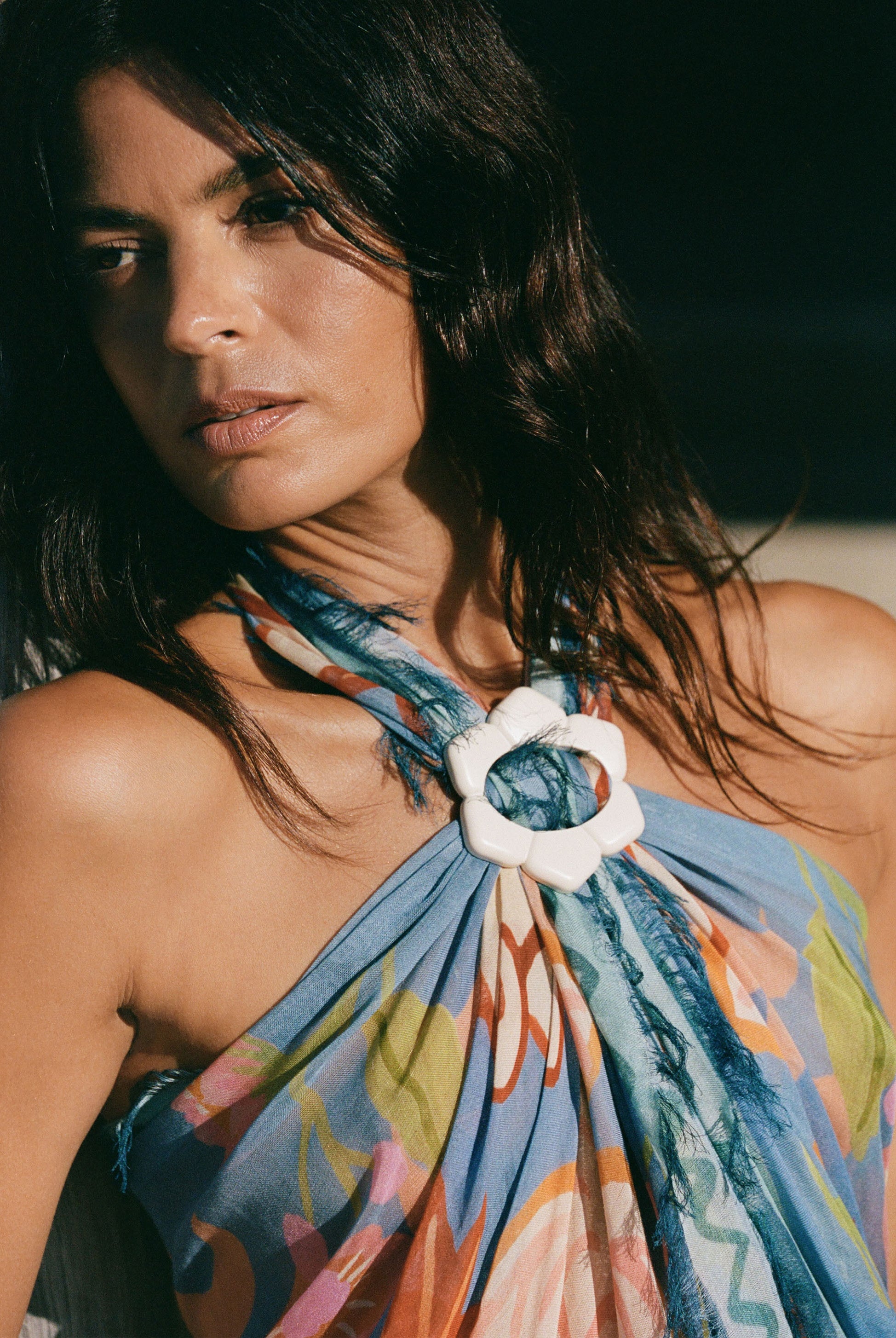 Woman wearing a colorful halter top with a white flower accessory.