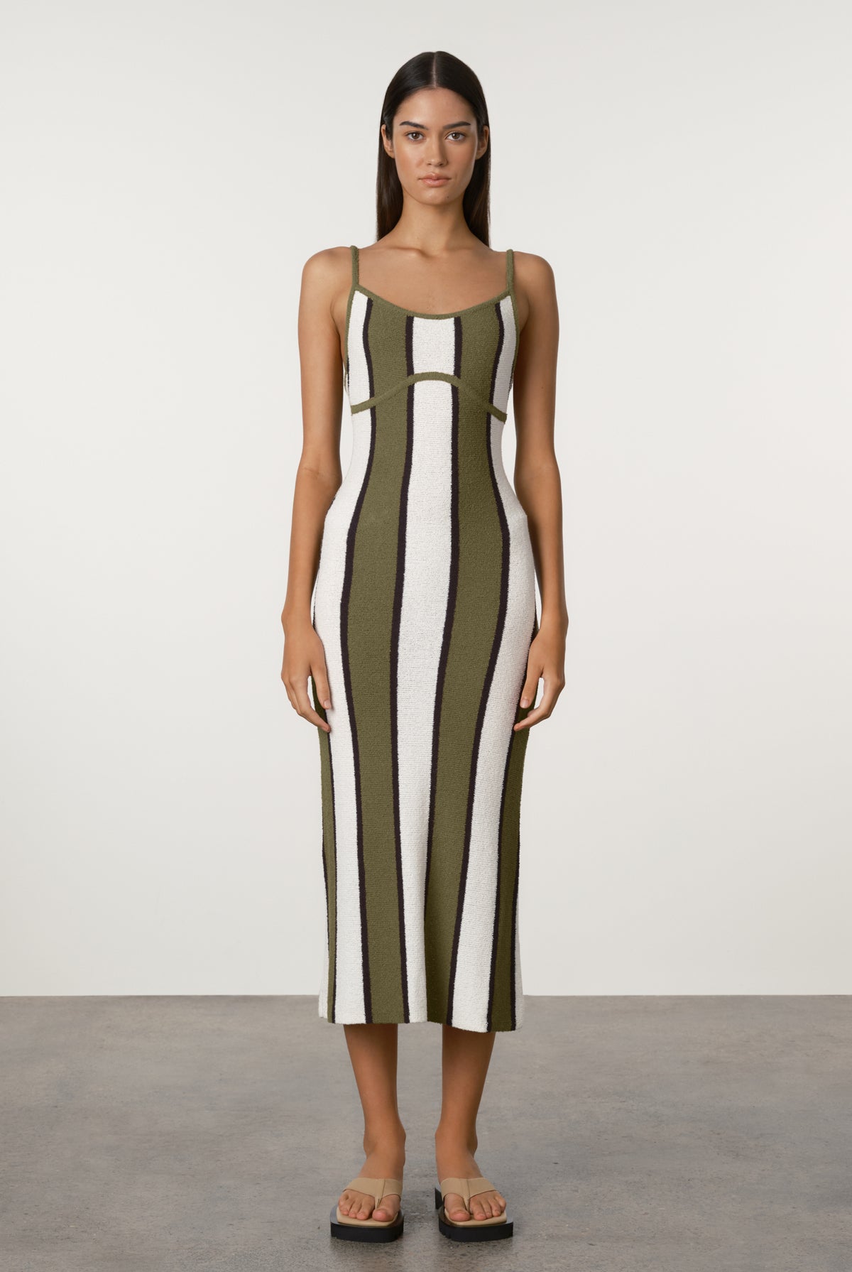 Woman wearing a green and white striped dress against a plain background