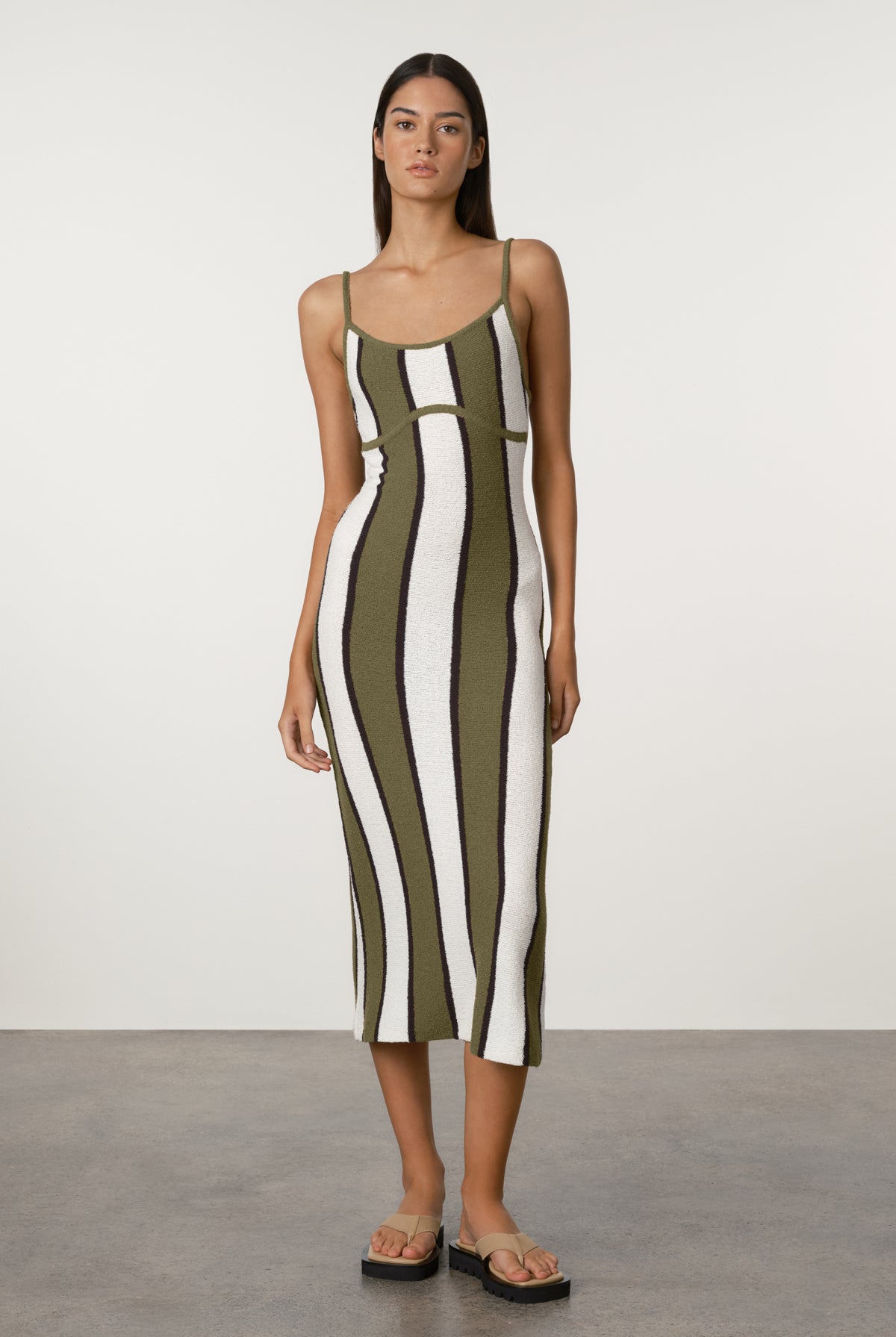 Woman wearing a green and white striped dress against a plain background