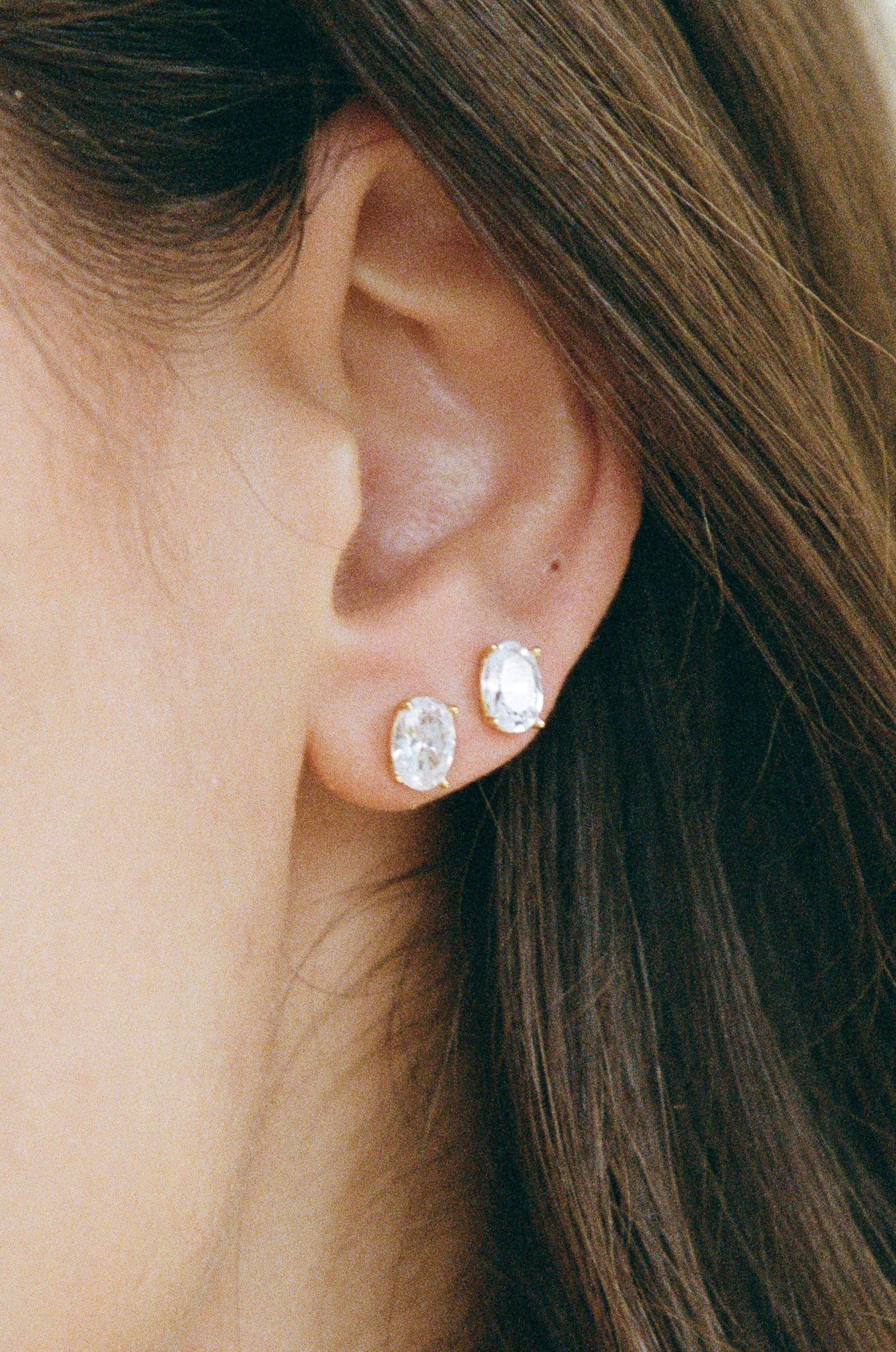 Close-up of an ear wearing two diamond stud earrings.