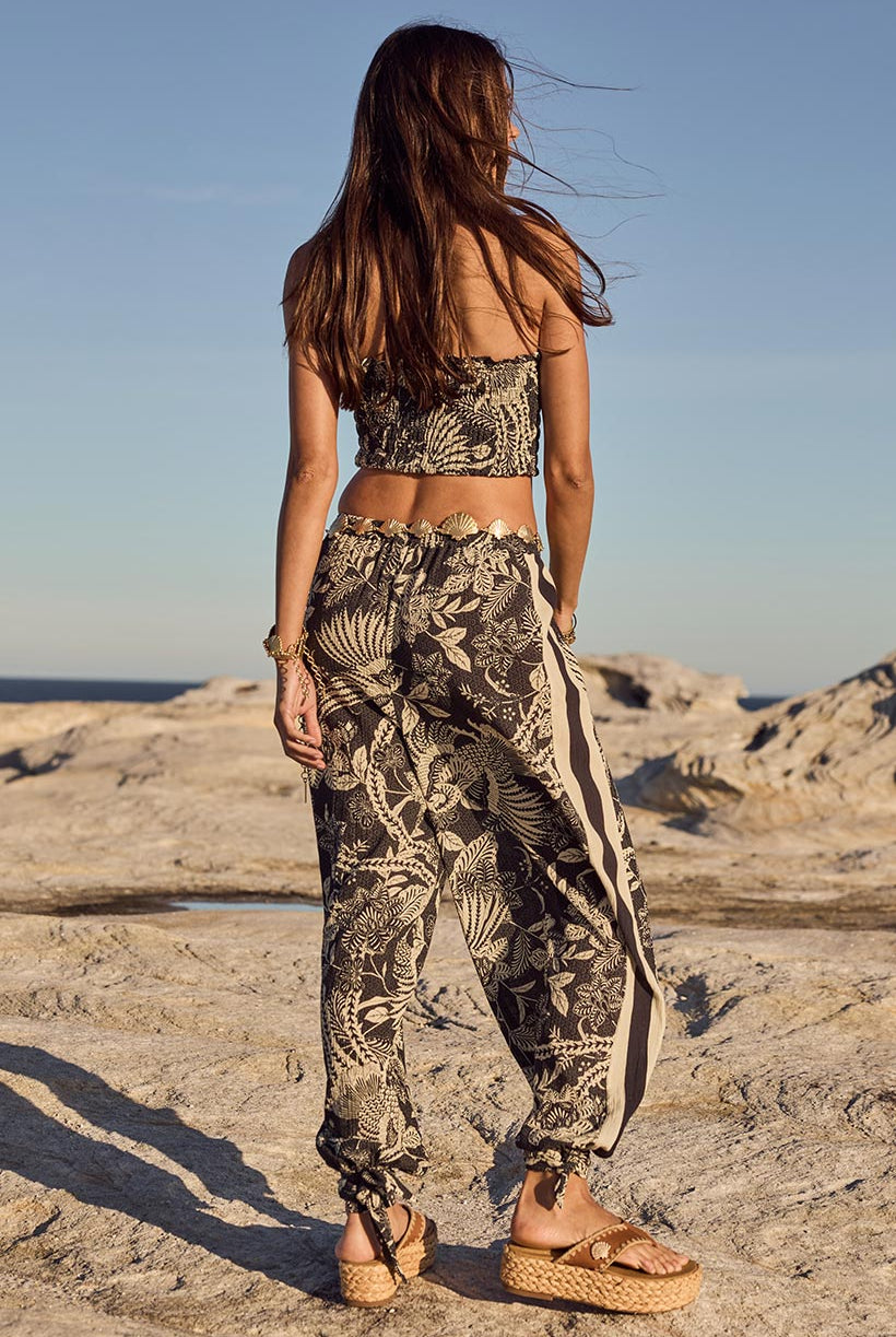 Woman in patterned outfit standing on a rocky beach